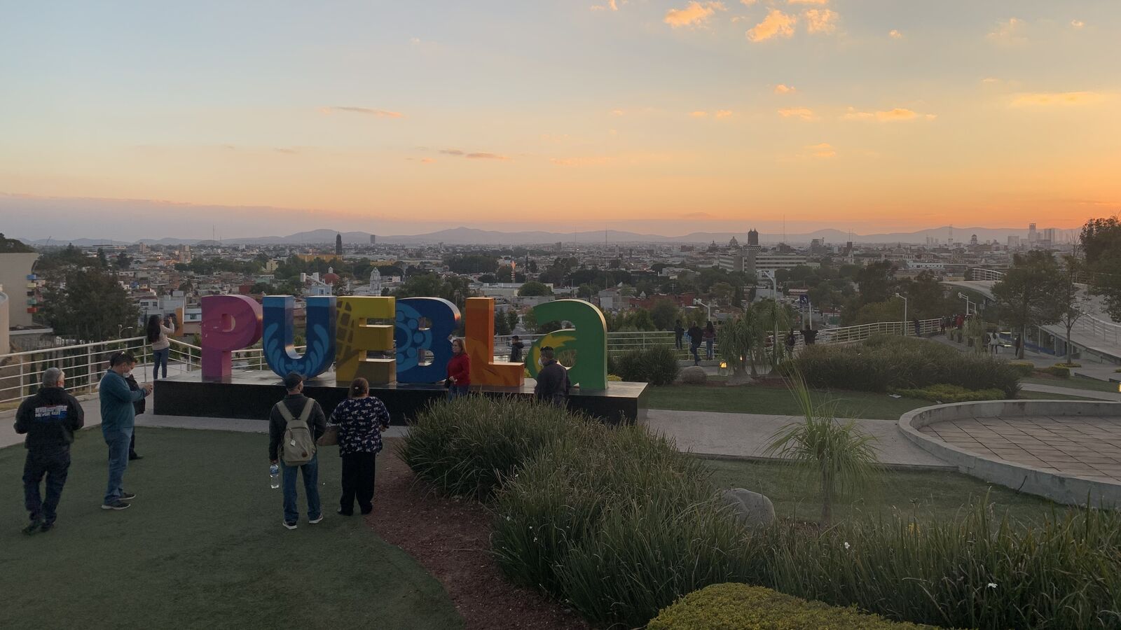 Der bunte Puebla-Schriftzug auf der Anhöhe Los Fuertes mit Blick über die Stadt Puebla im Abendlicht